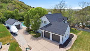 Expansive white stucco residence featuring a dark shingle roof, a three-car attached garage, a separate detached garage, an outdoor swimming pool, and a paved driveway