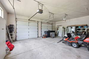 Spacious two-car garage featuring concrete flooring, overhead lighting, and an automatic garage door opener