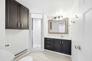 Bathroom featuring dark wood cabinetry, a white countertop, a framed mirror, a vanity light fixture, and a glass-enclosed shower