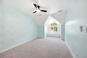 Room featuring a geometric accent wall, light blue painted walls, and gray carpet flooring