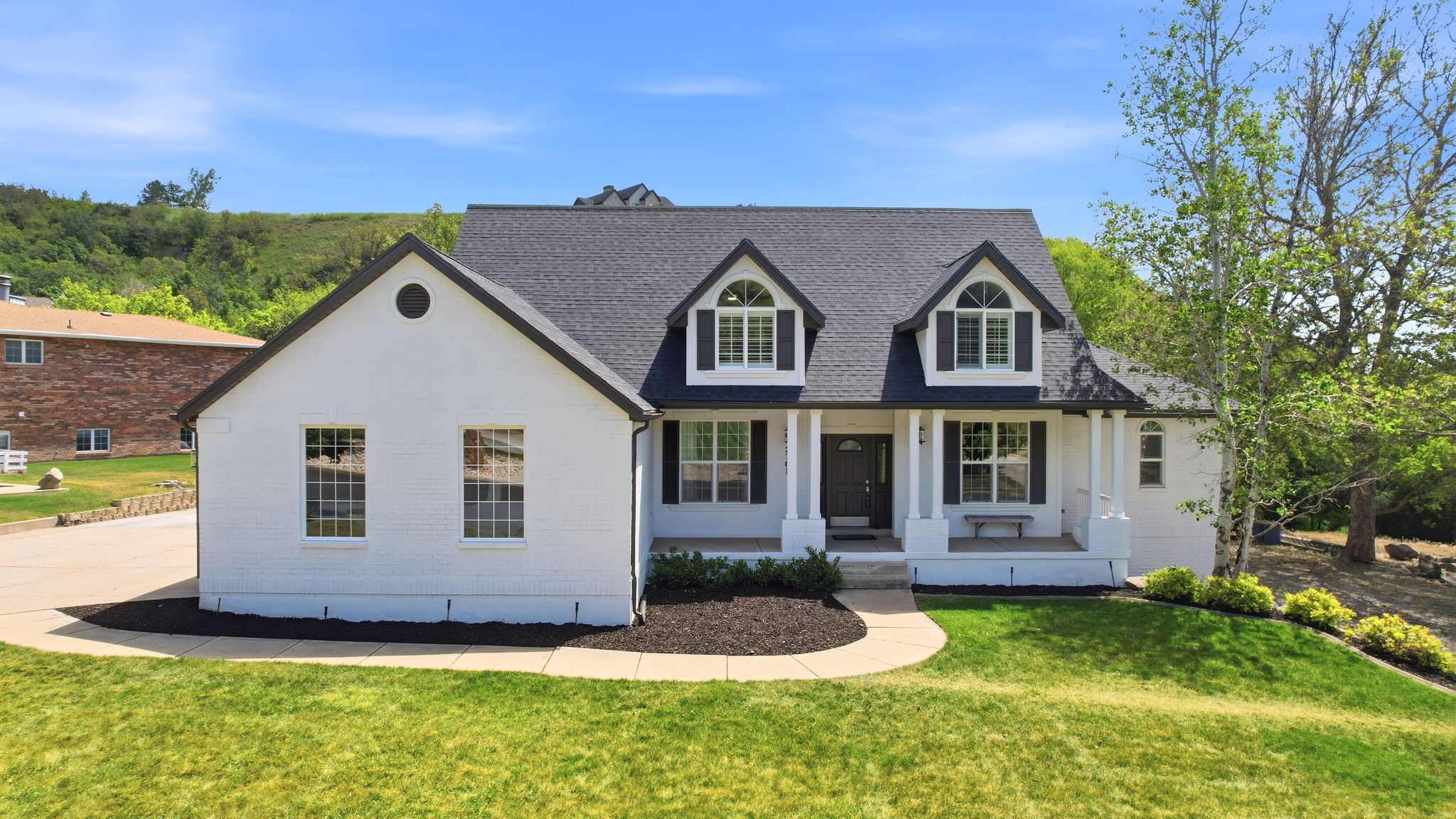 White brick exterior with a dark shingle roof and black shutters