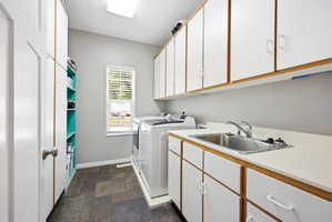 Utility room featuring extensive white cabinetry, a built-in stainless steel sink, large format floor tiling, a window with blinds, and recessed lighting