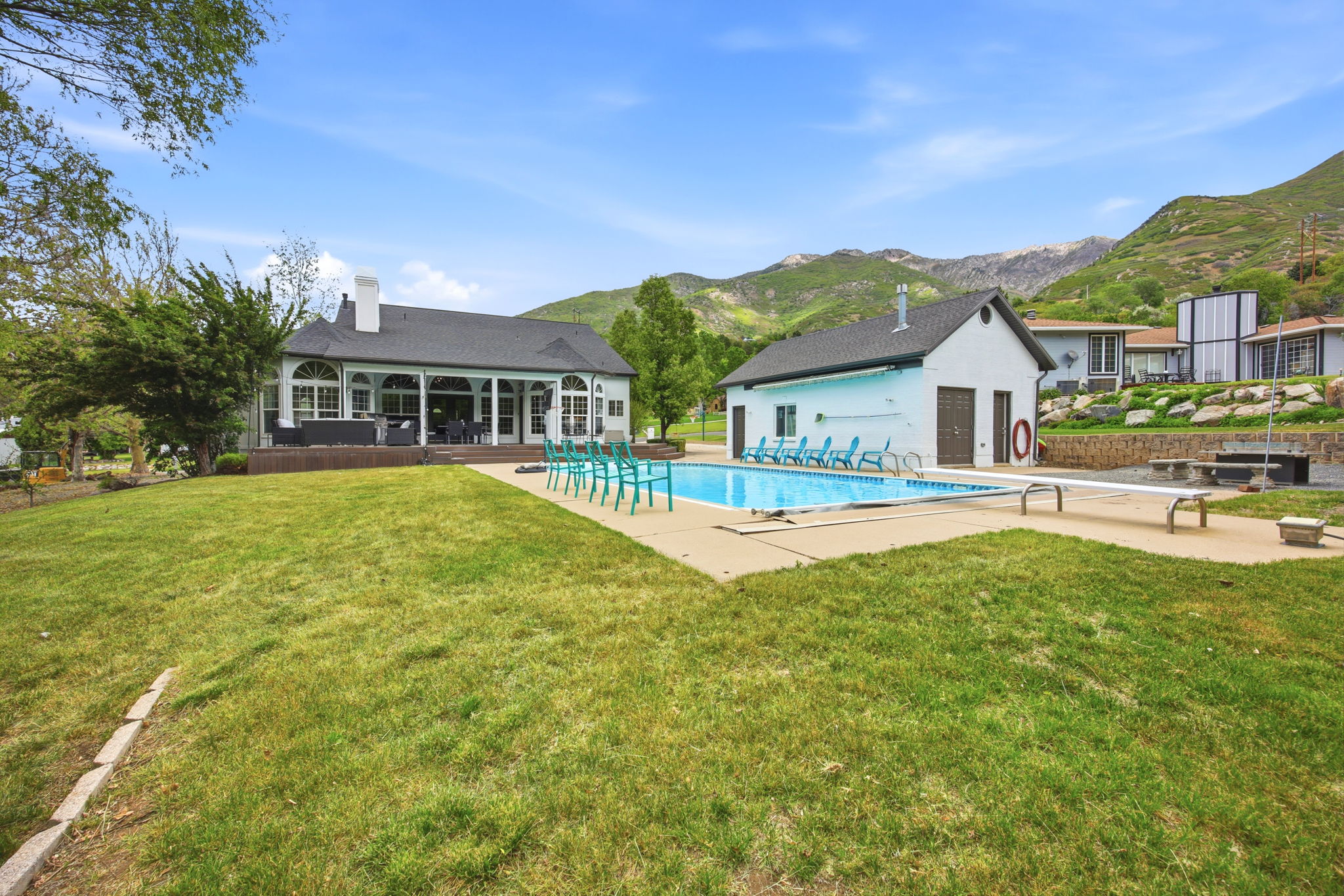 Expansive outdoor area featuring a swimming pool, adjacent pool house, and a spacious lawn