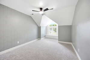 Carpeted room featuring an arched window, white plantation shutters, and a window seat