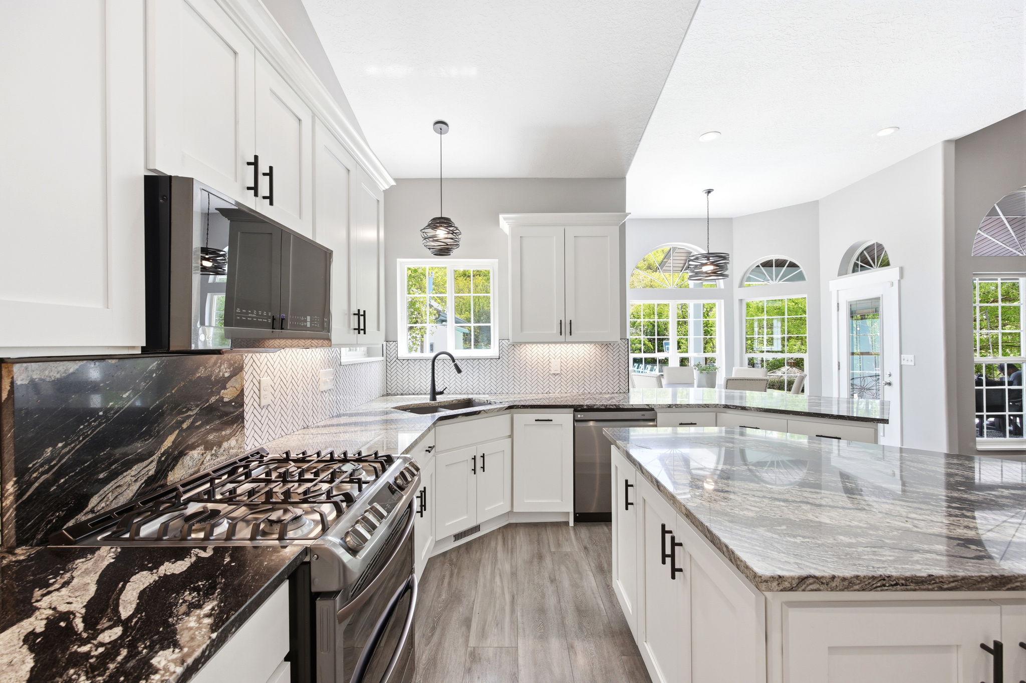 Gourmet kitchen featuring a stainless steel range, white shaker cabinetry, black and grey patterned countertops, a white herringbone tile backsplash, and wood-finish flooring