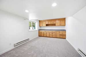 Light gray carpeted flooring complements a wall of built-in wood cabinetry featuring extensive countertop space
