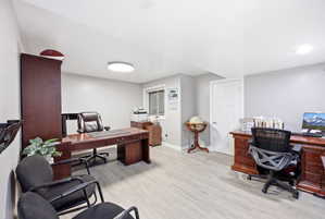 Spacious room featuring wood-finish flooring, light gray walls, a window with horizontal blinds, and a white paneled door