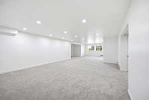 Spacious room featuring light gray carpeting, recessed ceiling lighting, and multiple windows providing natural illumination