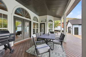 Spacious covered deck featuring wood-finish flooring and multiple arched transom windows