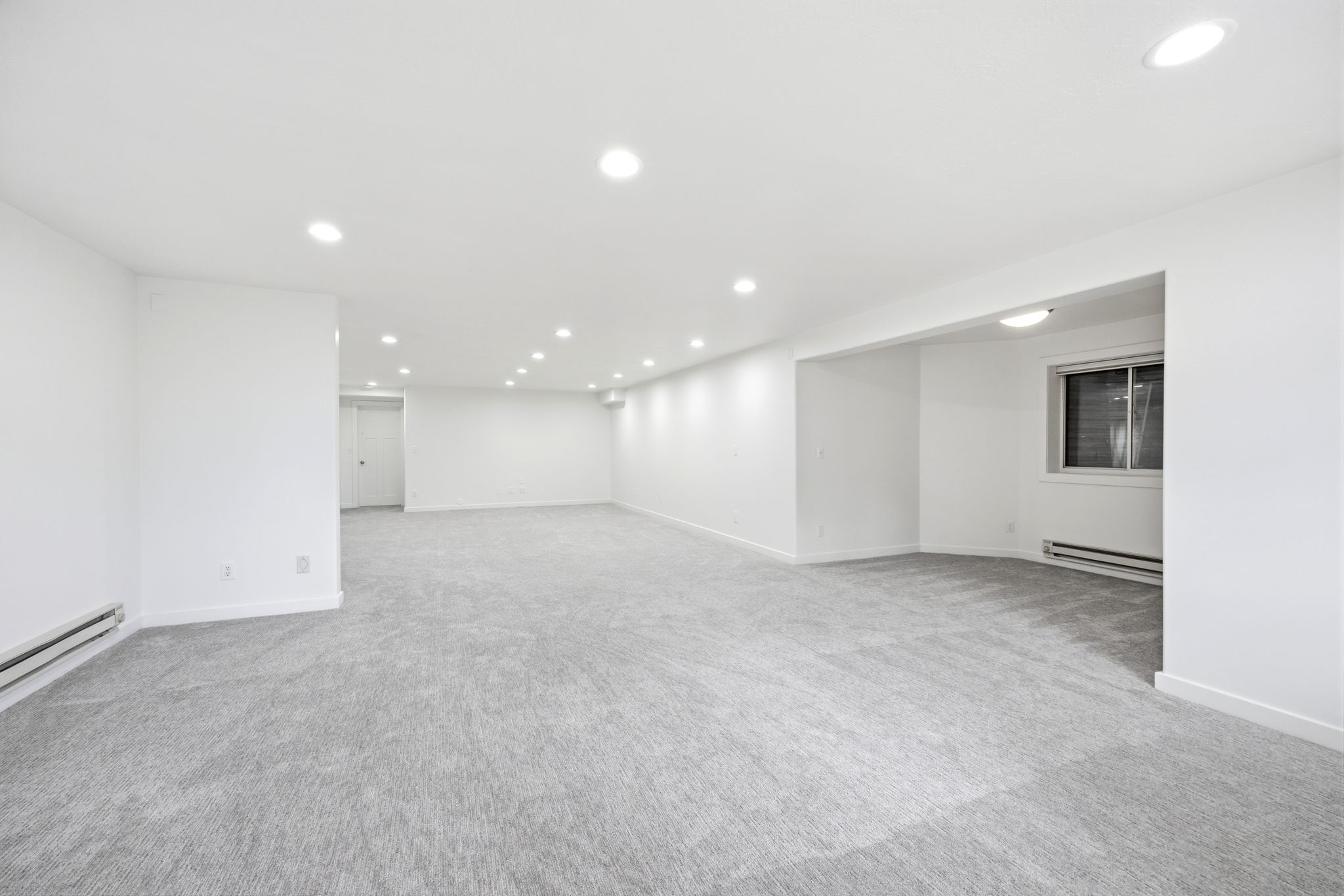 Expansive interior space featuring light gray carpeting and white walls