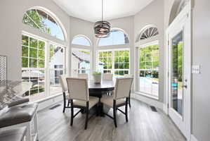 Dining area with expansive window wall, arched transoms, and wood-finish flooring