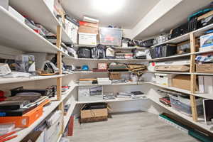 Spacious storage room featuring extensive built-in shelving, durable wood-finish flooring, and bright overhead lighting