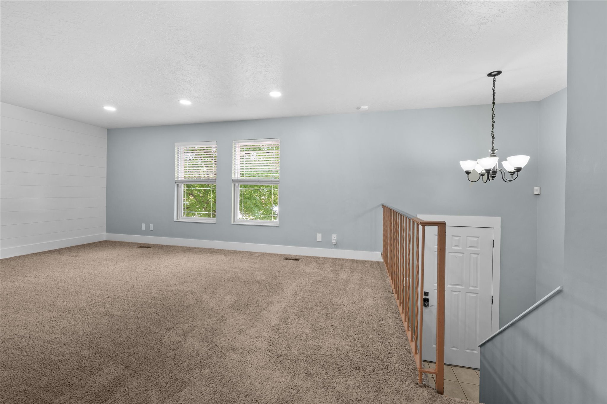Upper-level living area with neutral carpeting and a shiplap accent wall