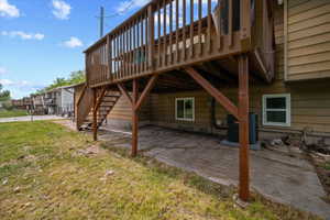 Elevated wood deck with baluster railing, offering access to a concrete patio