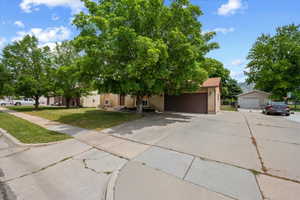 Property exterior with a two-car garage, mature front yard trees, and a concrete driveway and RV pad