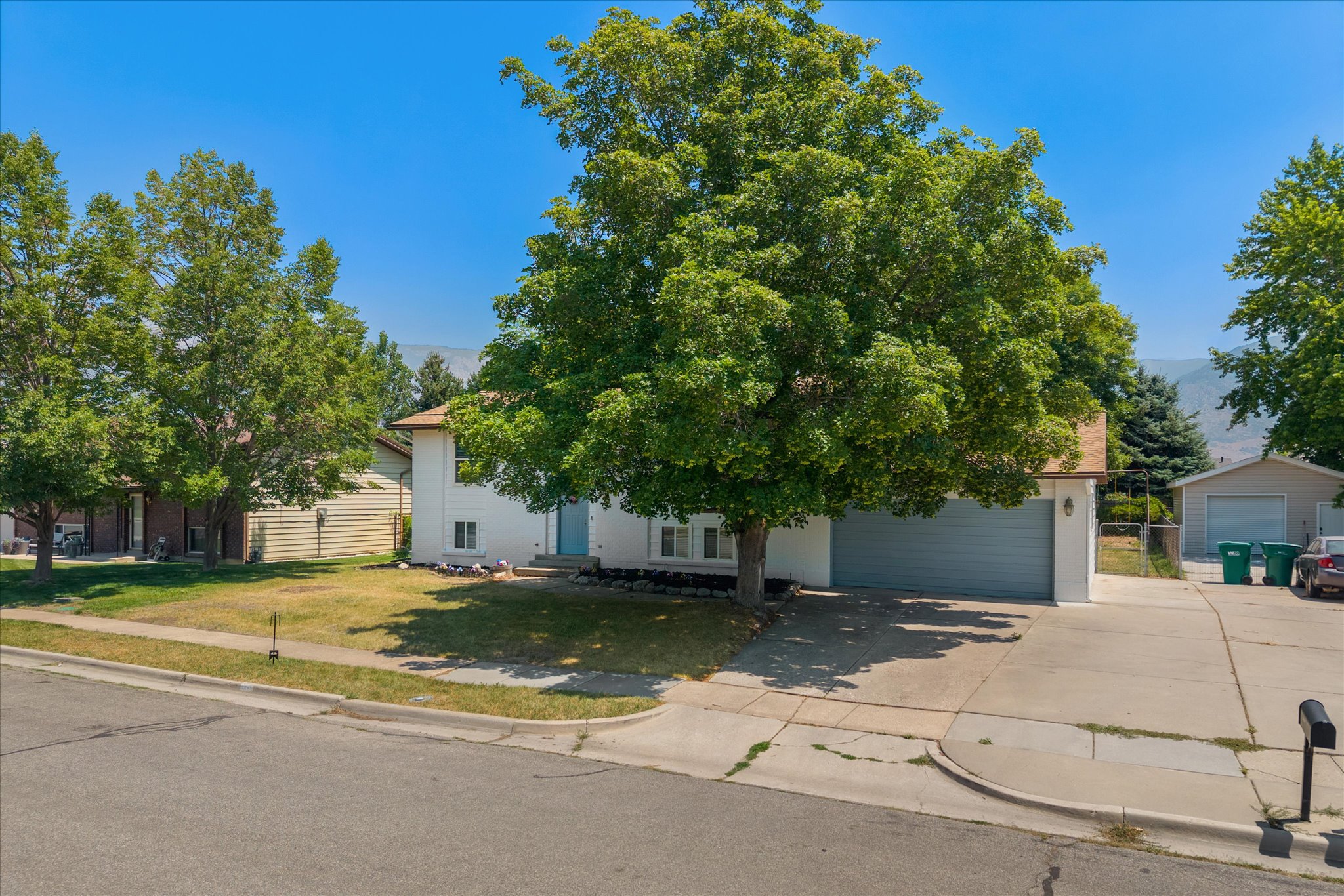 Two-story residence featuring a two-car garage, established front yard tree, and an additional detached garage with an extended driveway