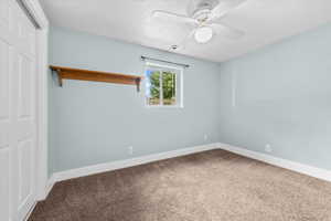 Bedroom #4 with Light blue interior wall, window with exterior landscape, built-in wooden shelf, and a ceiling fan with light fixture