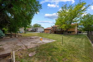 Expansive backyard featuring a 12x12 concrete patio, mature trees, and a raised vegetable garden