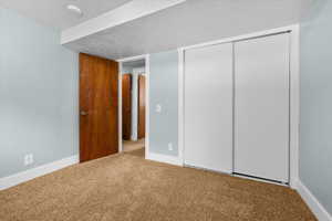 Interior bedroom #3  featuring light blue walls, brown carpet, white baseboards, and a white sliding closet door