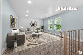 Spacious living area featuring light blue walls, recessed lighting, double windows, and light wood-finish railings
