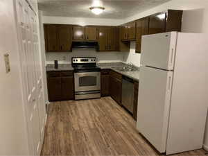 Kitchen featuring wood-finish flooring, dark wood cabinetry, and granite-look countertops