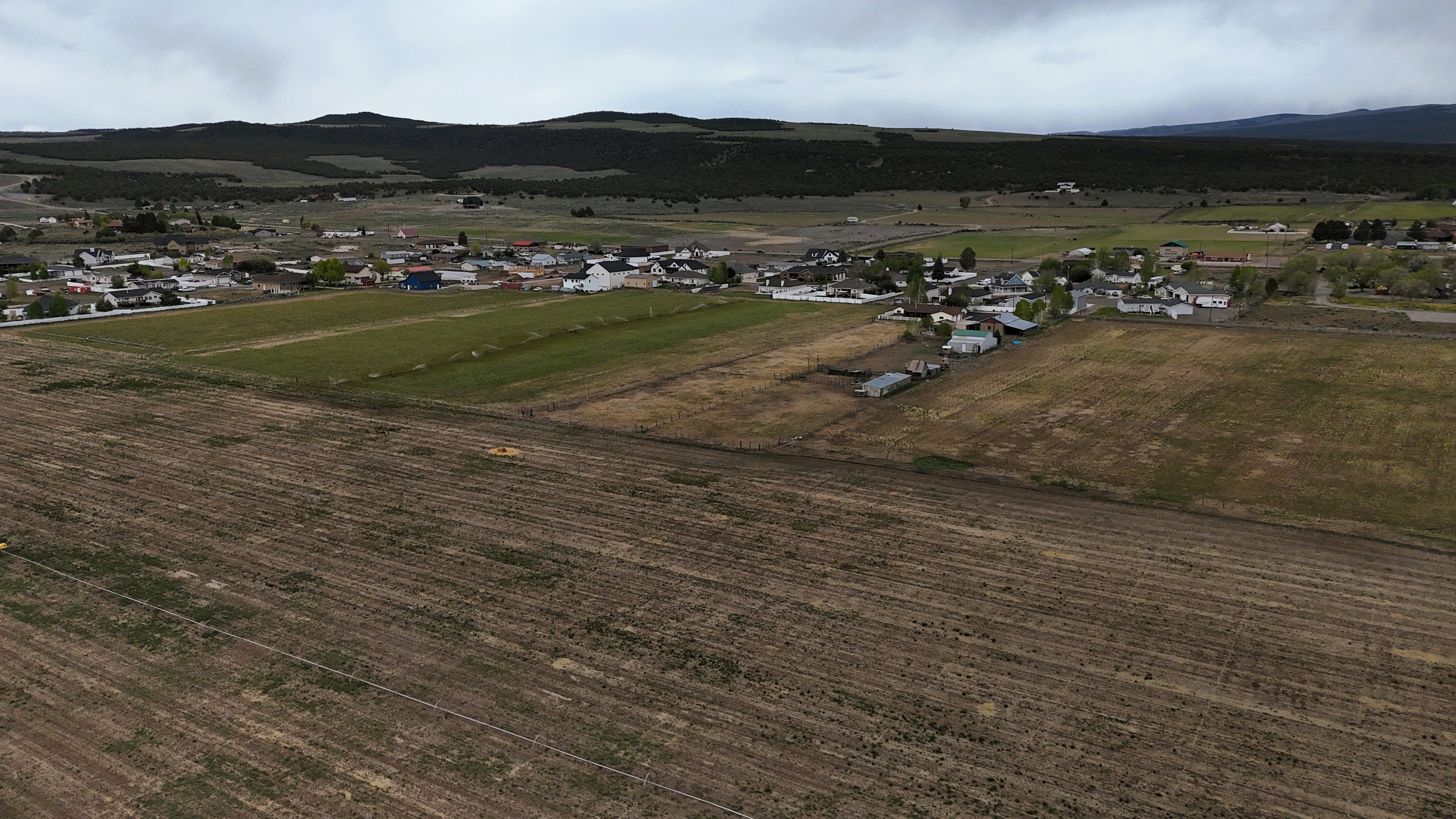Expansive undeveloped land featuring a rural landscape with distant residential structures and natural, rolling hills