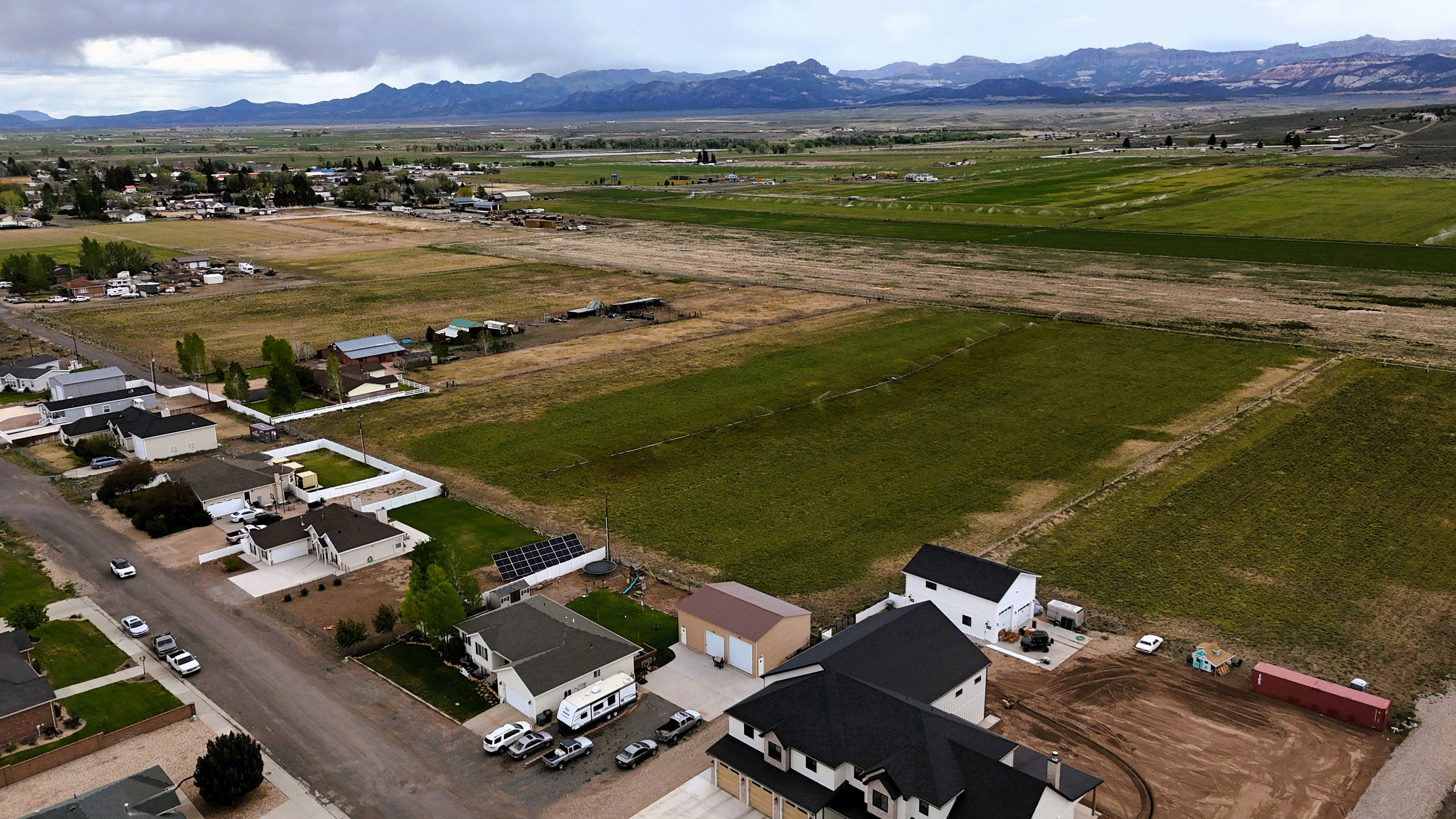 Expansive land parcels featuring established residential areas, open fields, and distant mountain backdrops