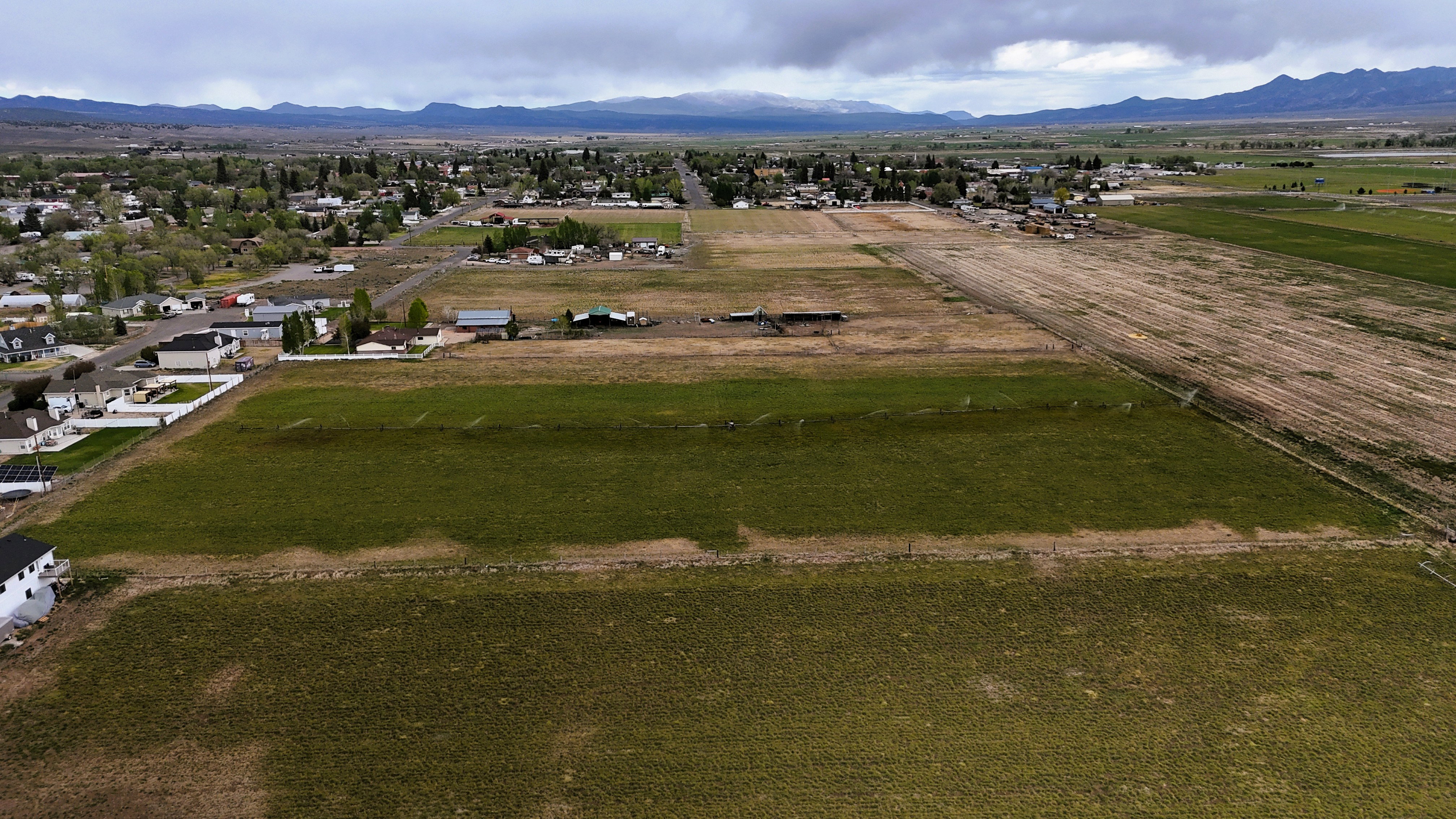 Expansive land parcel featuring a mix of open fields and distant residential structures
