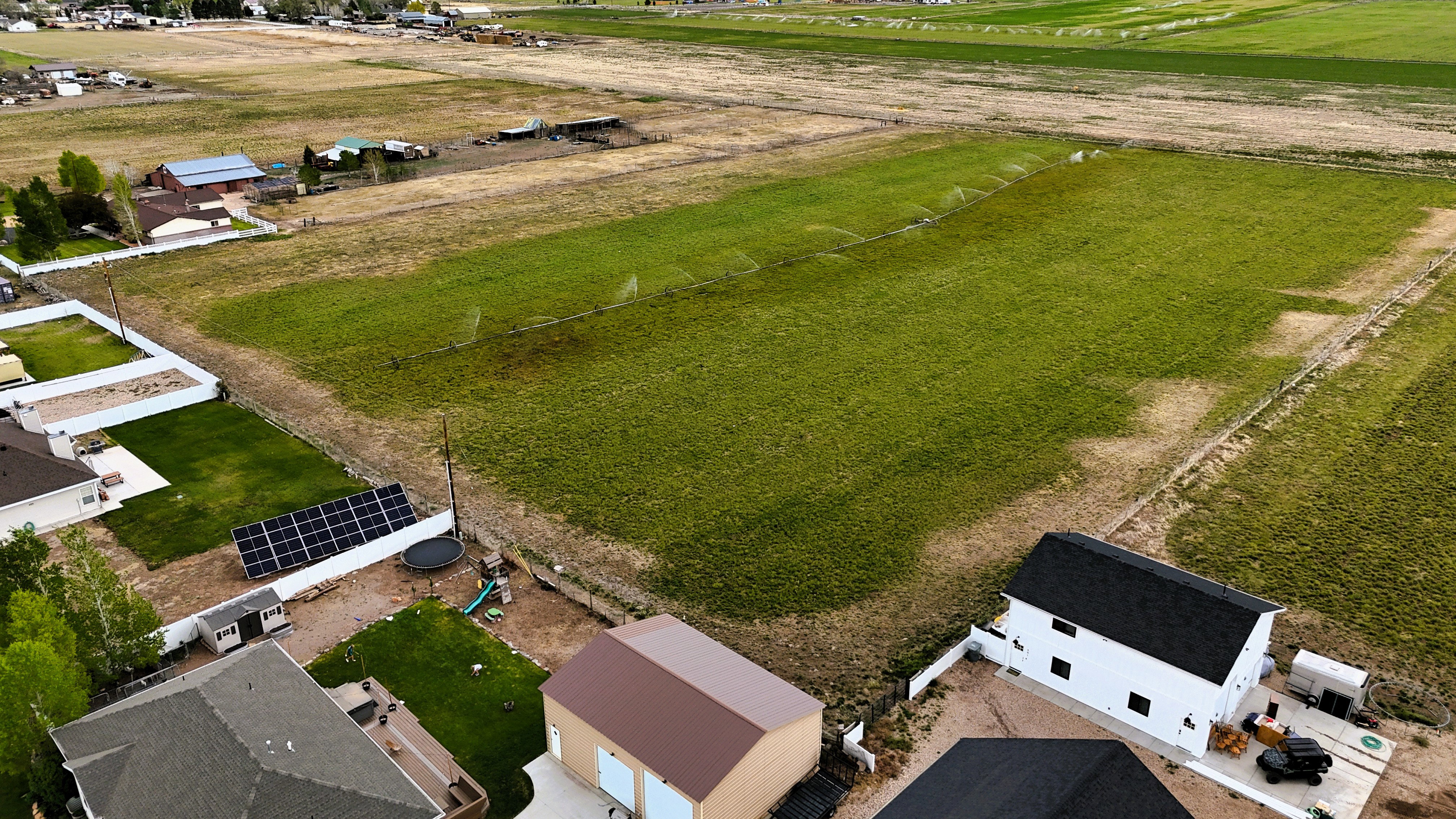 Expansive green fields extending into the distance, bordered by a white fence