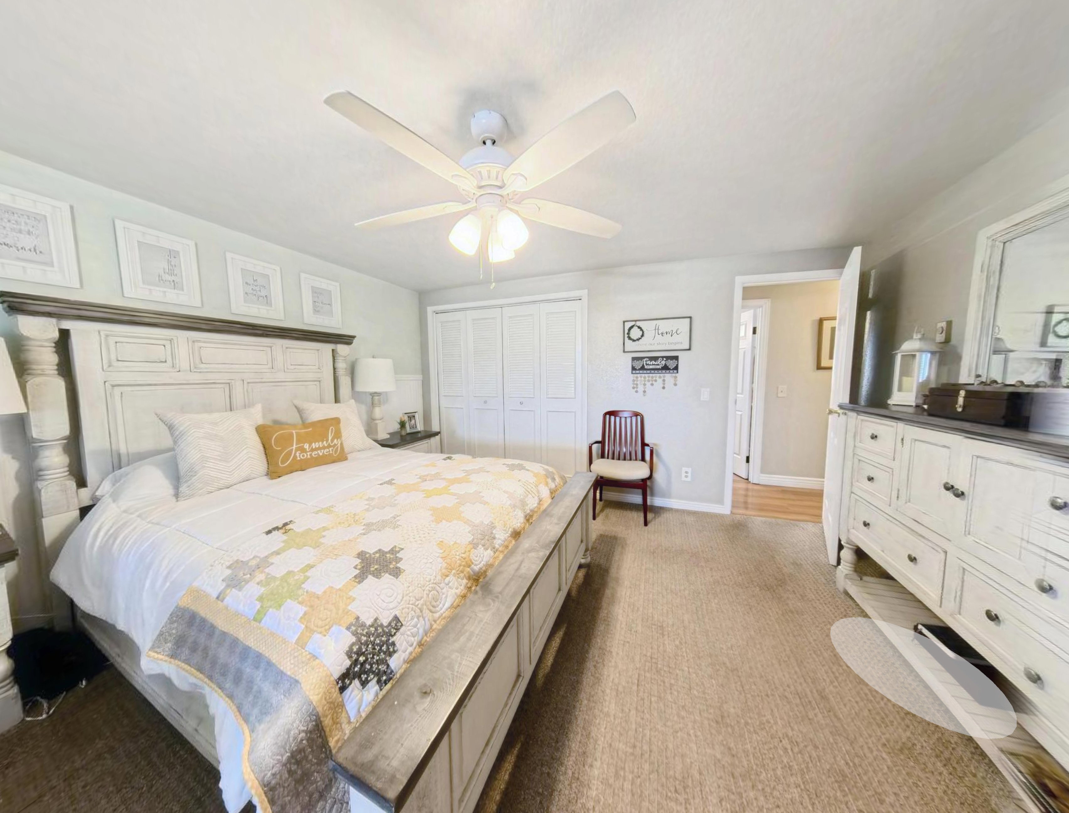 Bedroom featuring light neutral wall paint, a ceiling fan with integrated lighting, bi-fold closet doors, and light-toned carpeting