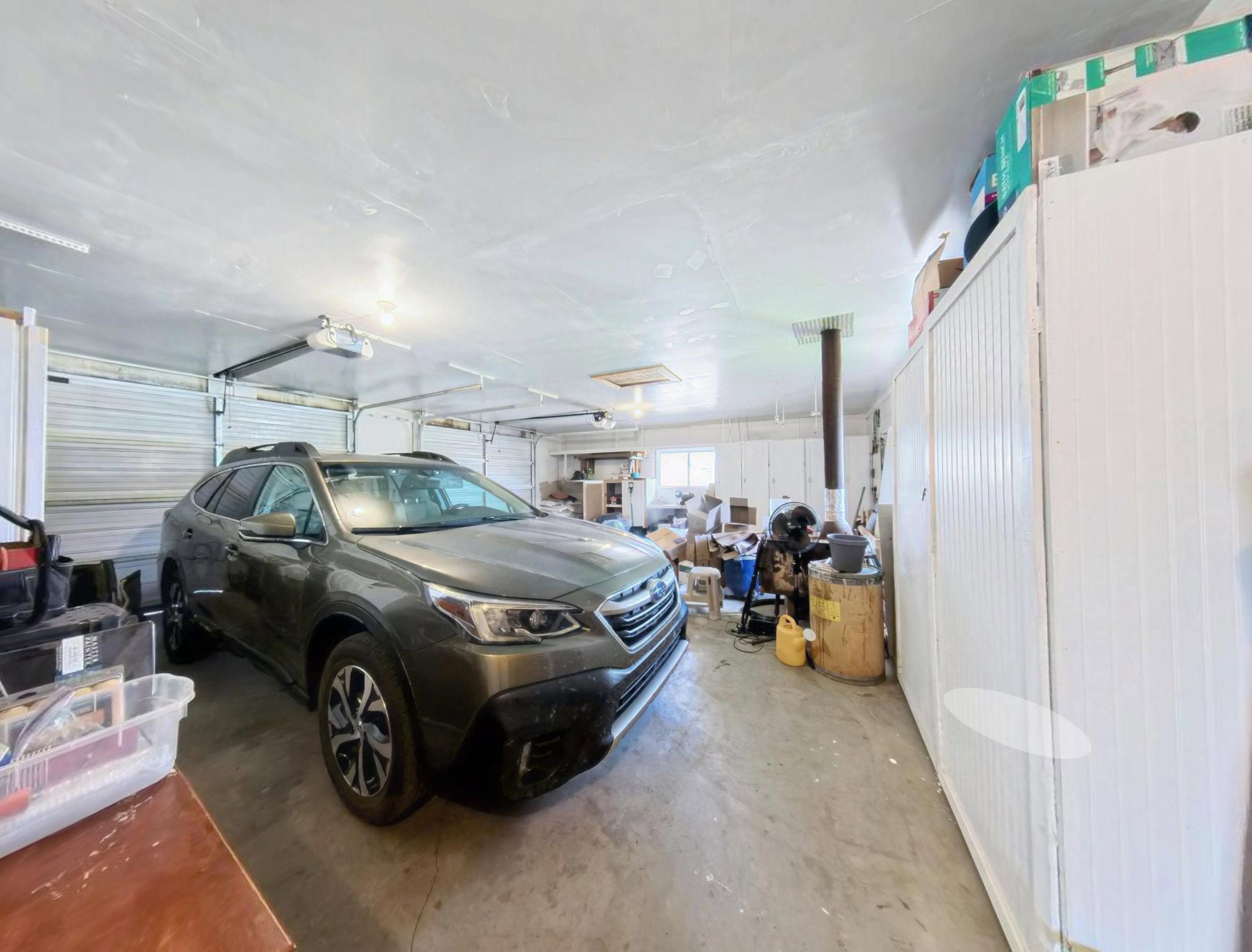 Spacious garage featuring a concrete floor, overhead lighting, and white walls