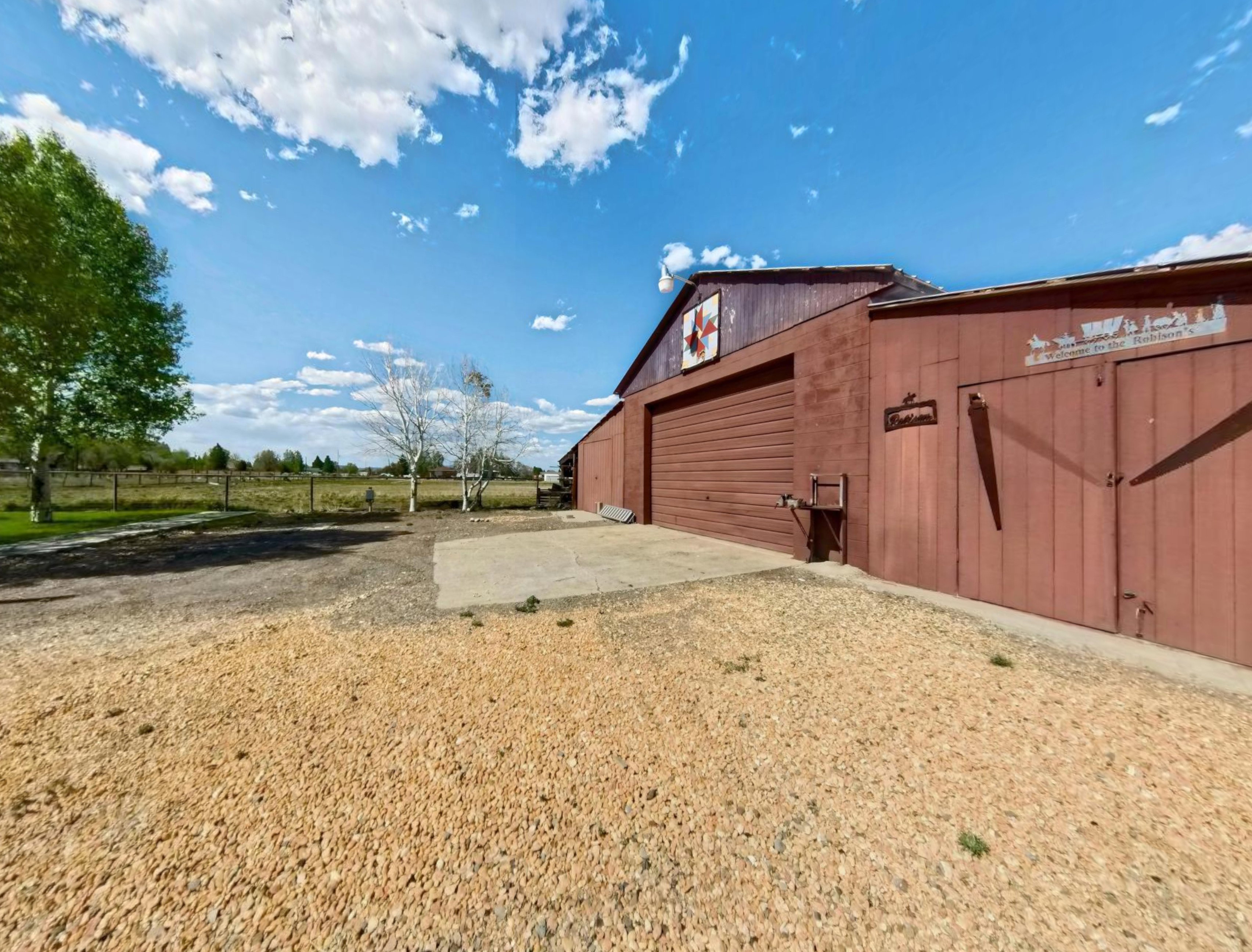 Red-sided barn with an attached storage area, featuring a large roll-up door and a smaller wooden double door