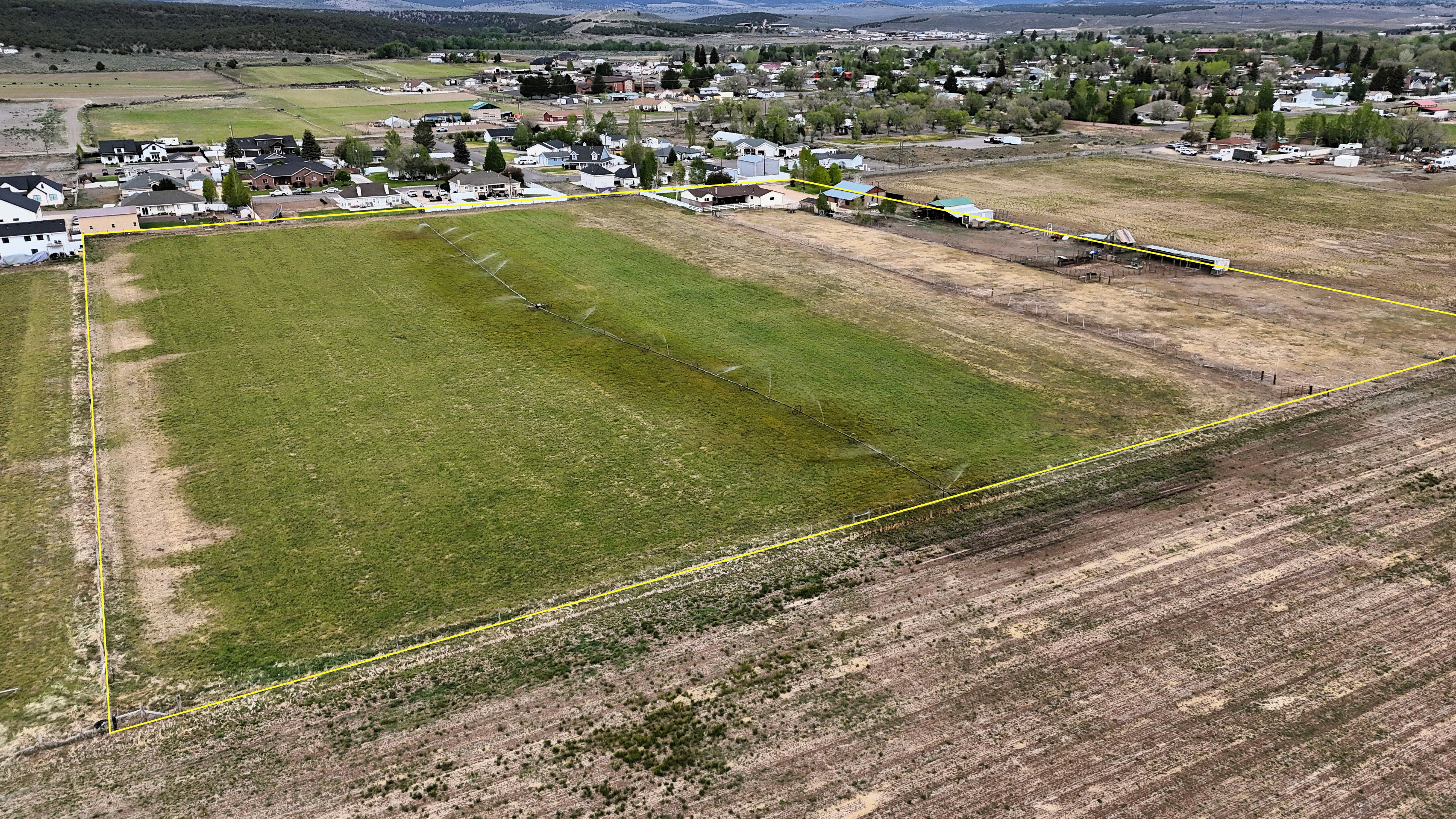 Expansive agricultural land featuring a partially tilled field and a green pasture area