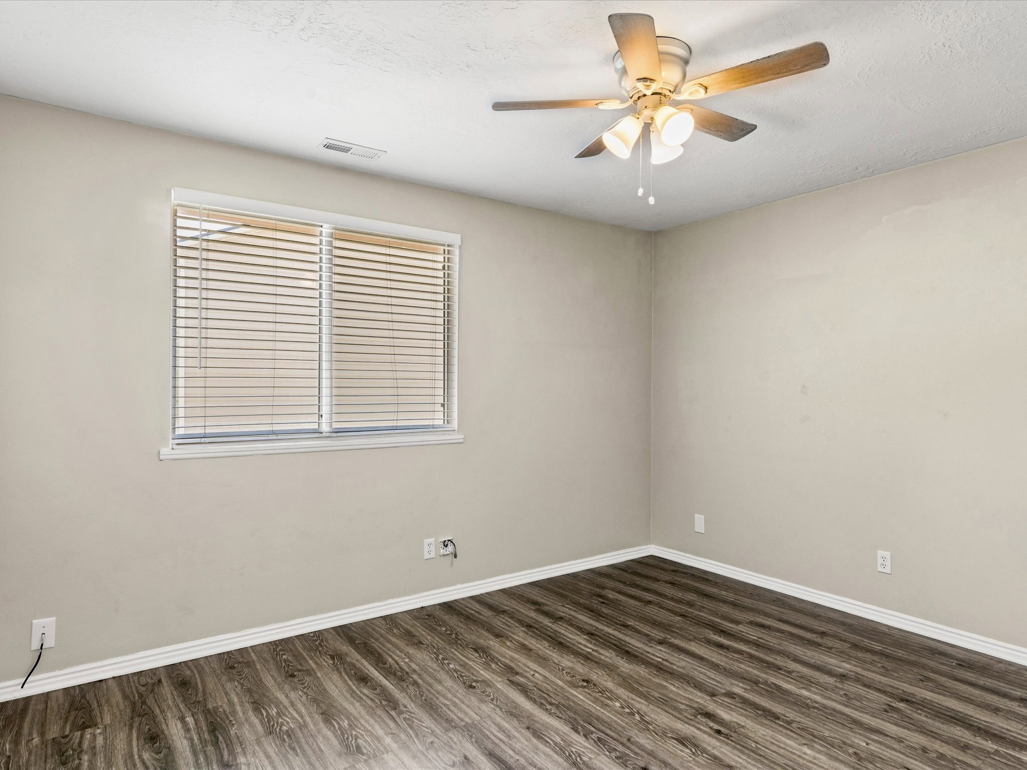 Room featuring wood-finish flooring, neutral wall tones, and white baseboards