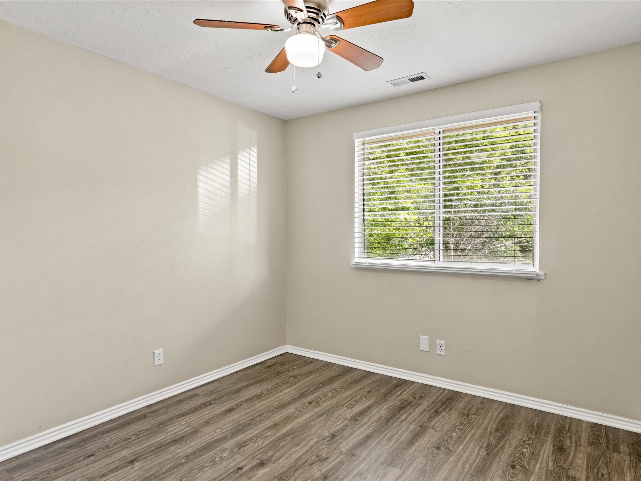 Room with wood-finish flooring, neutral-toned walls, and white baseboards