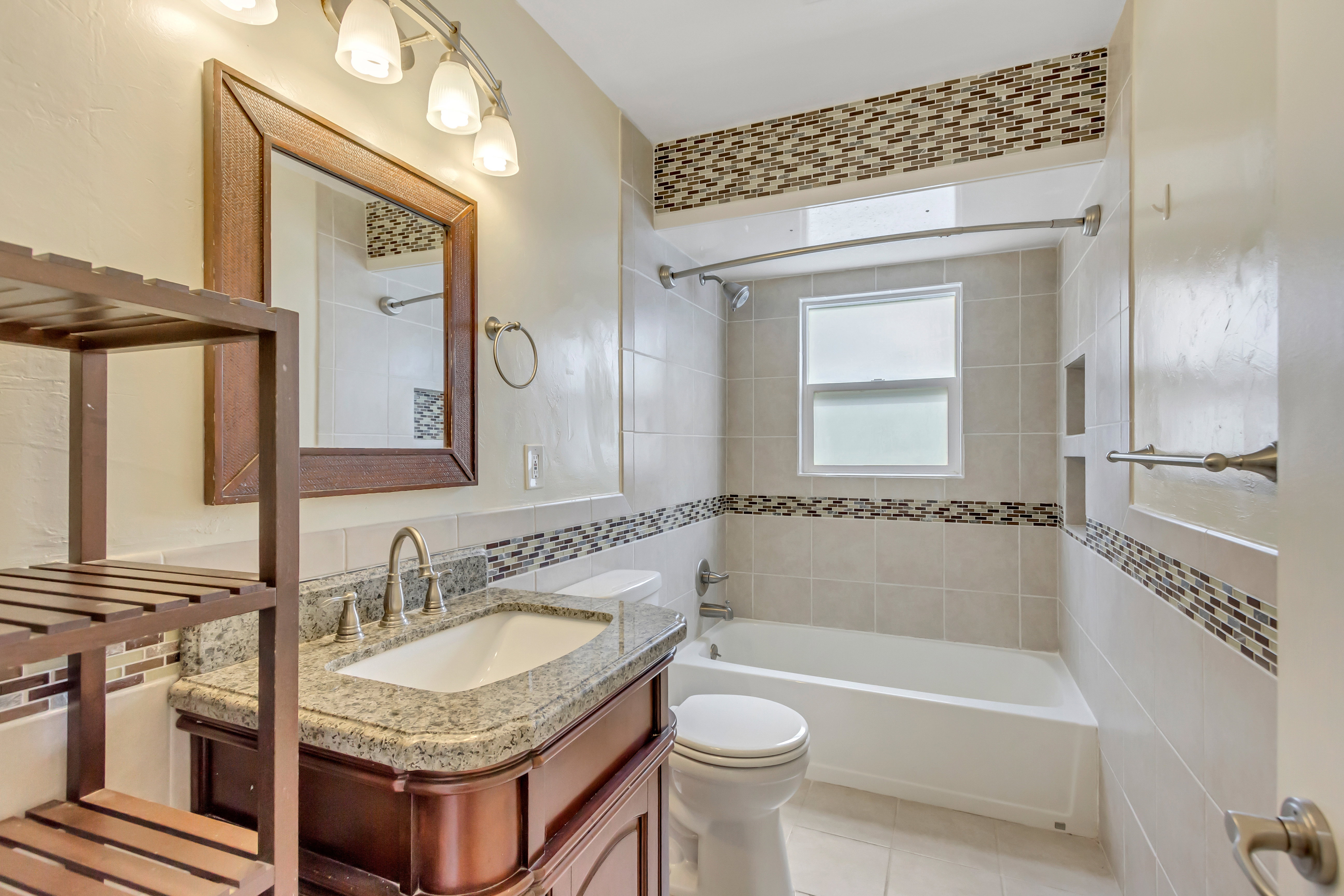 Bathroom featuring a vanity with a granite countertop, undermount sink, and wood-framed mirror