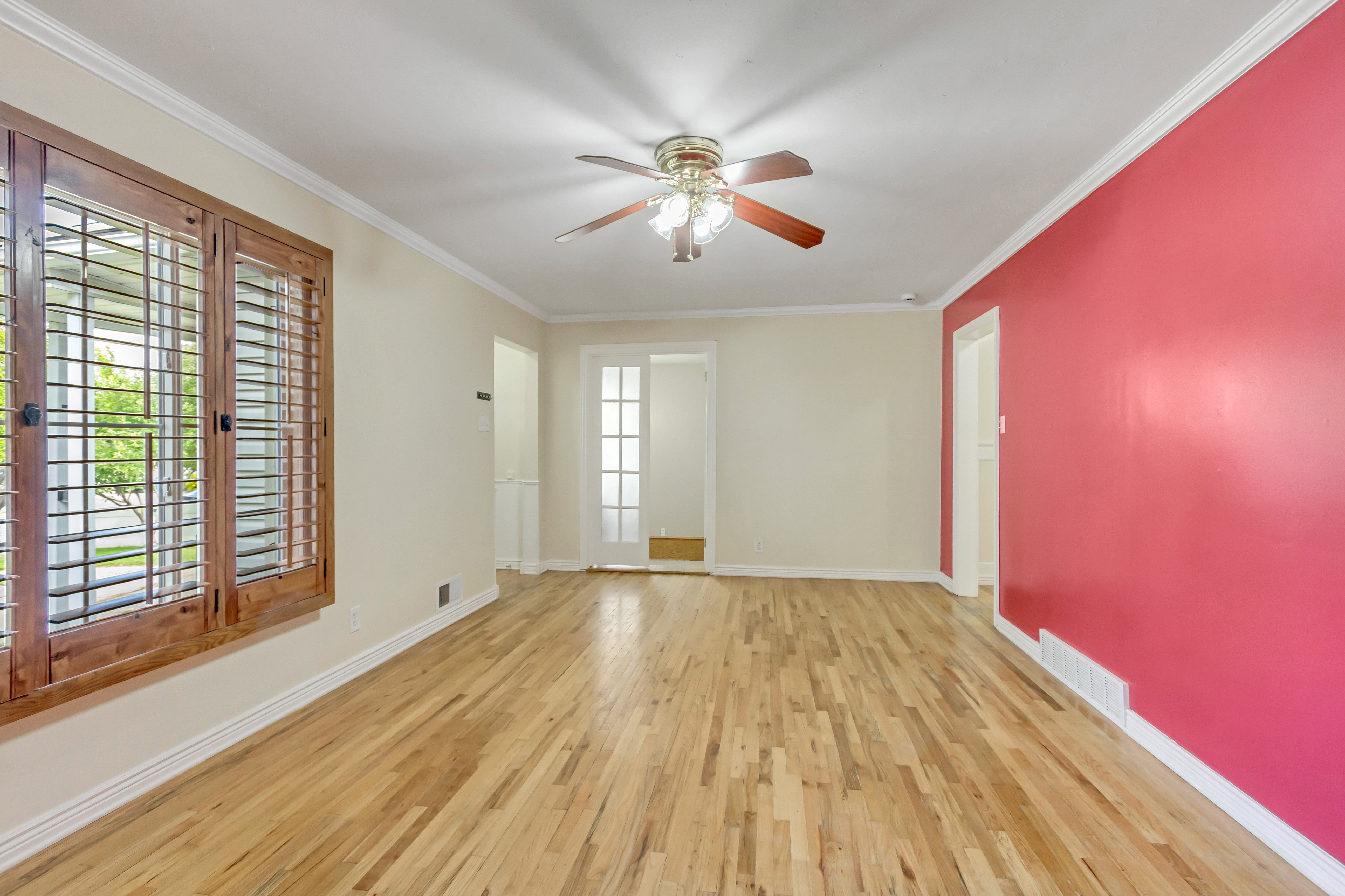 Spacious interior featuring wood-finish flooring, a ceiling fan with light, and crown molding