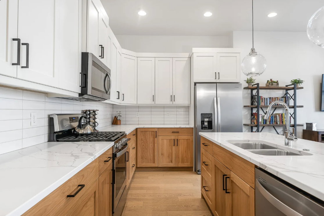 Bright kitchen featuring a two-tone cabinetry design with white upper cabinets and wood-finish lower cabinets