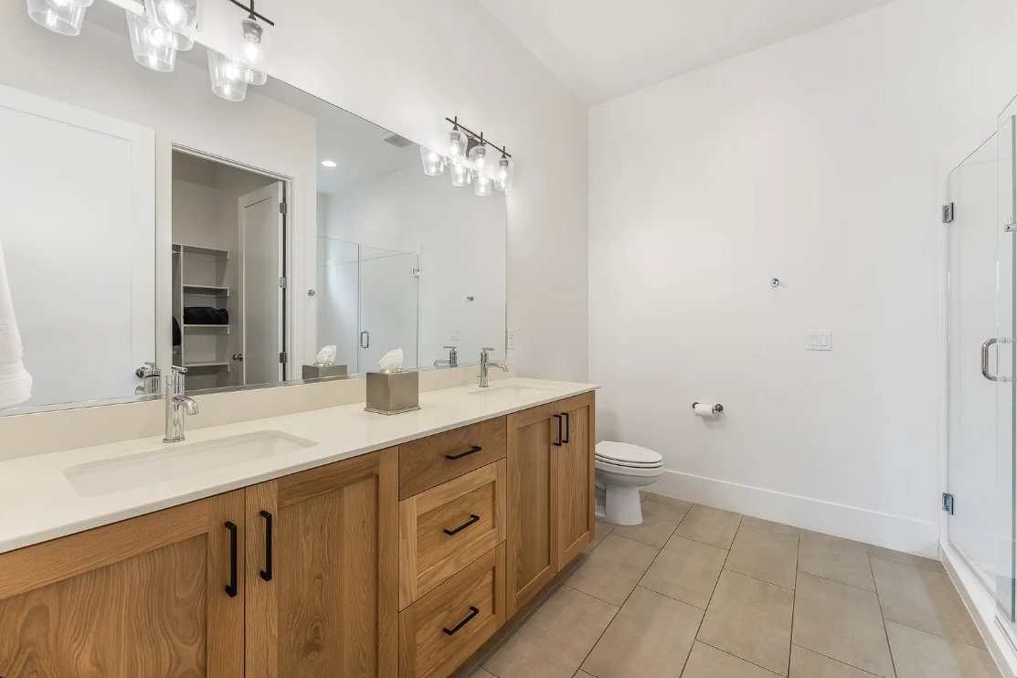 Dual vanity with light wood-finish cabinetry, integrated sinks, and polished chrome faucets
