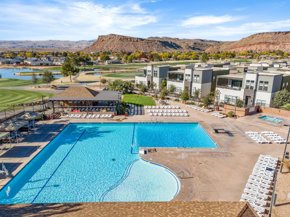 Expansive aquatic amenity area featuring a large rectangular pool with integrated shallow entry, surrounding lounge deck, and separate spa