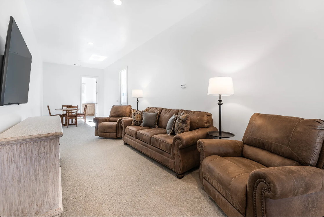 Open concept living space with light-colored carpeting and white walls