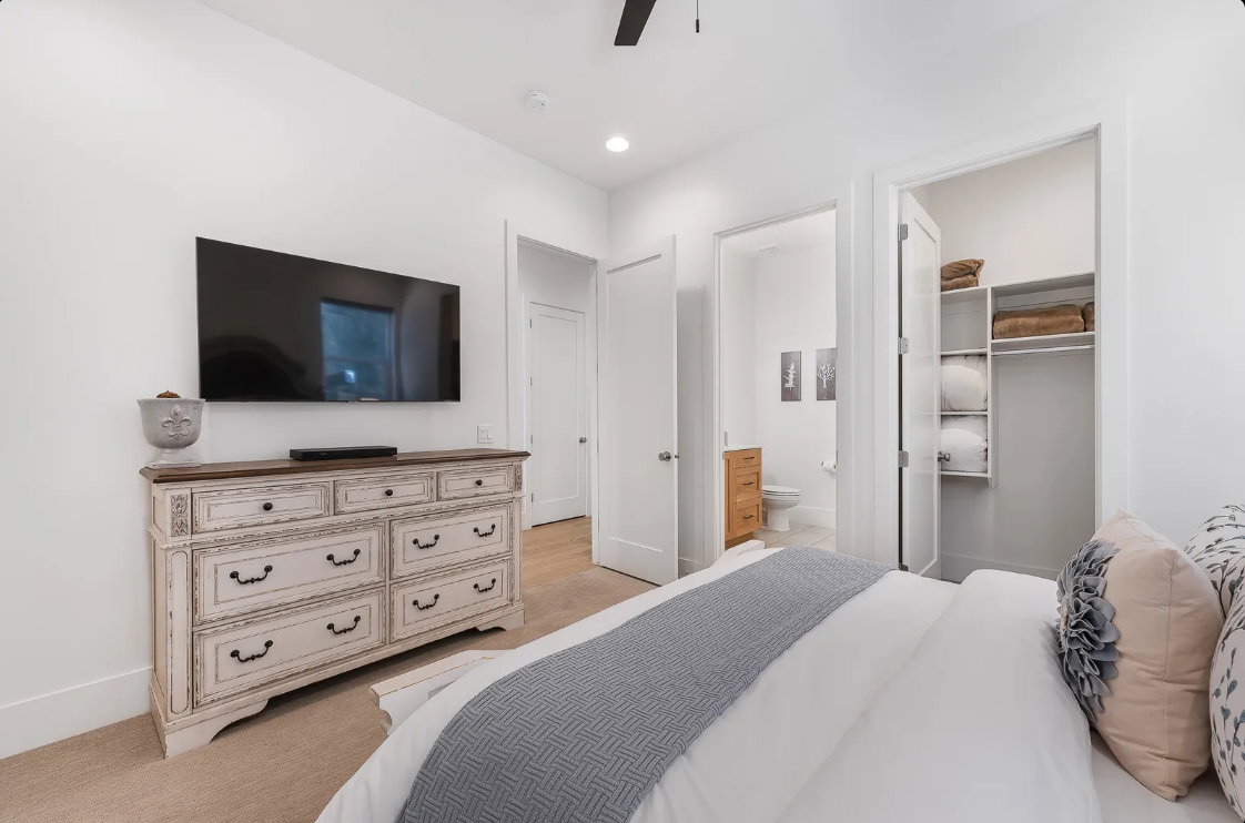 Recessed lighting illuminates this bright room featuring carpet flooring and a built-in closet with shelving