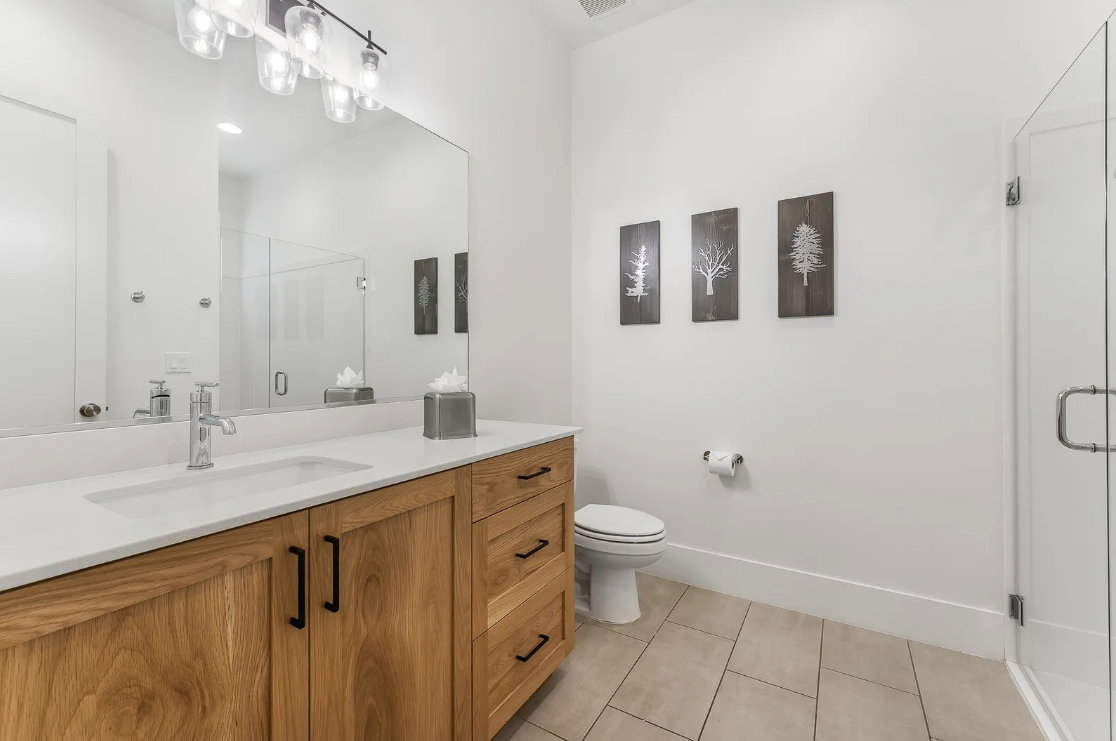 Bathroom featuring a light wood-finish vanity with black hardware, white countertop, and integrated sink