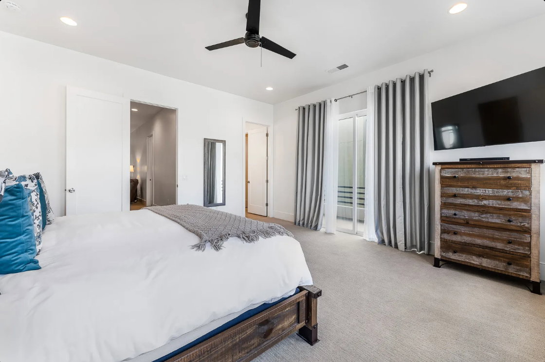 Spacious room featuring light-toned carpeting, white walls, and a black ceiling fan