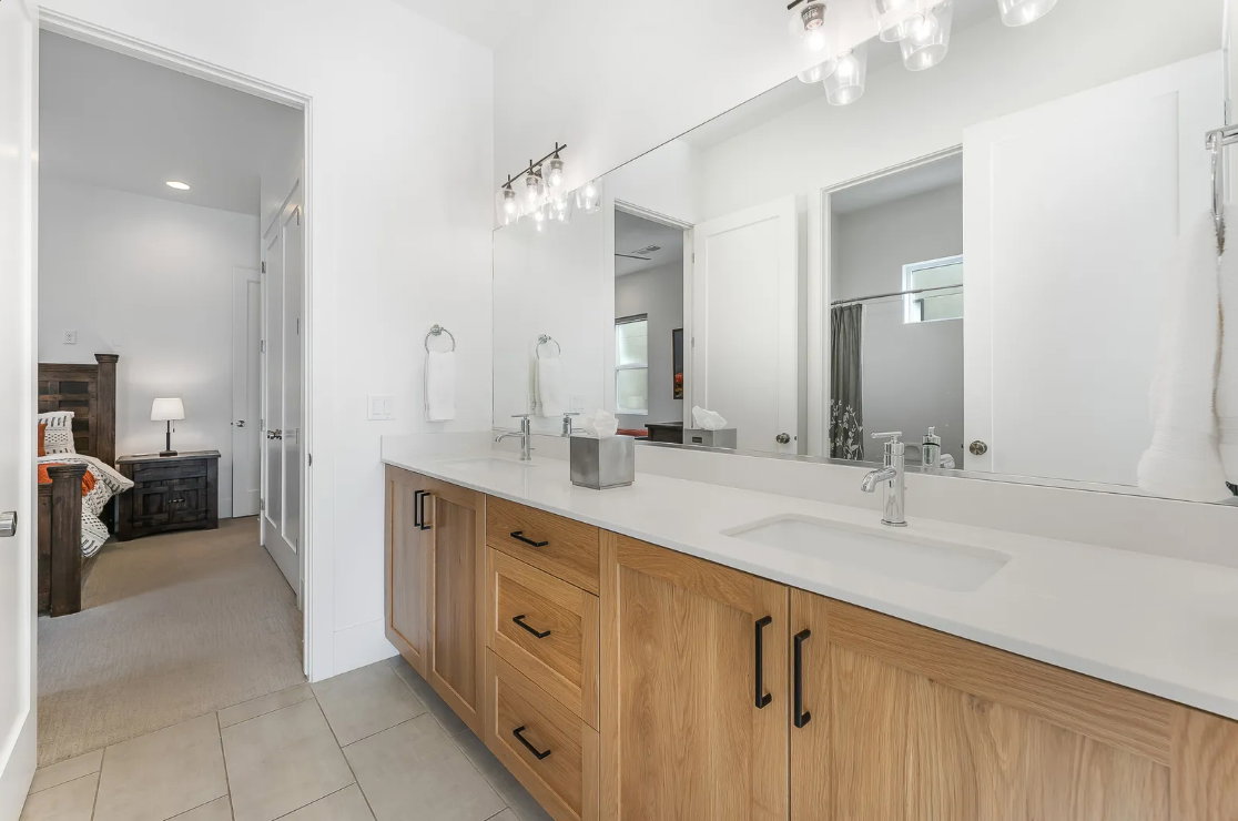 Double vanity featuring light wood-finish cabinetry and white countertops