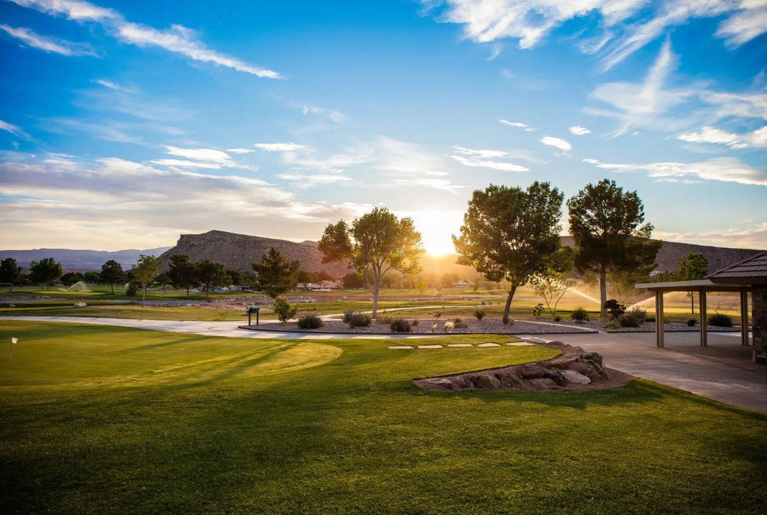 Expansive golf course property featuring manicured greens, a paved cart path, and a putting green with flag