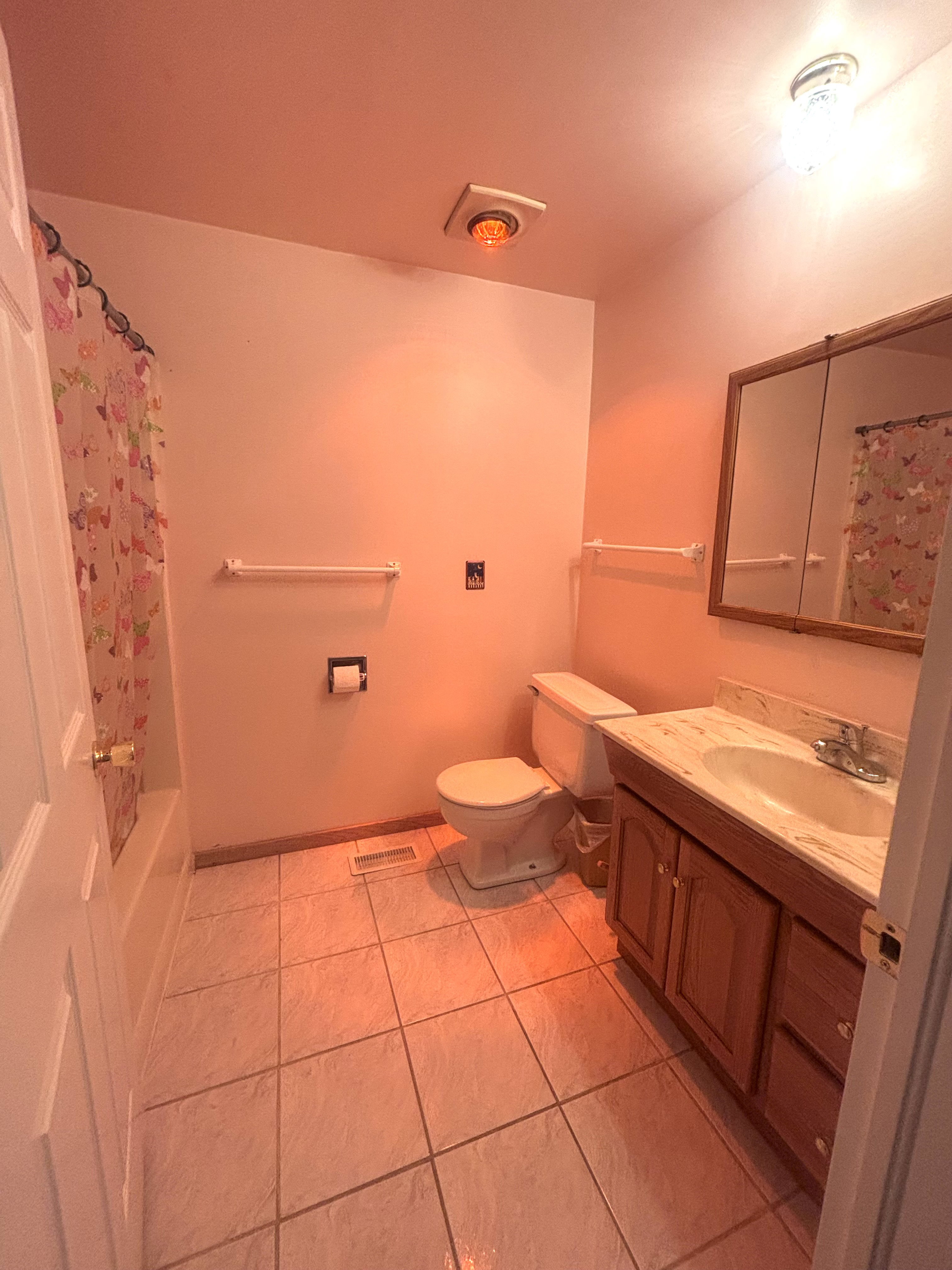 Bathroom featuring tile flooring, a built-in vanity with cabinetry, a wall-mounted mirror, and a full bathtub with shower