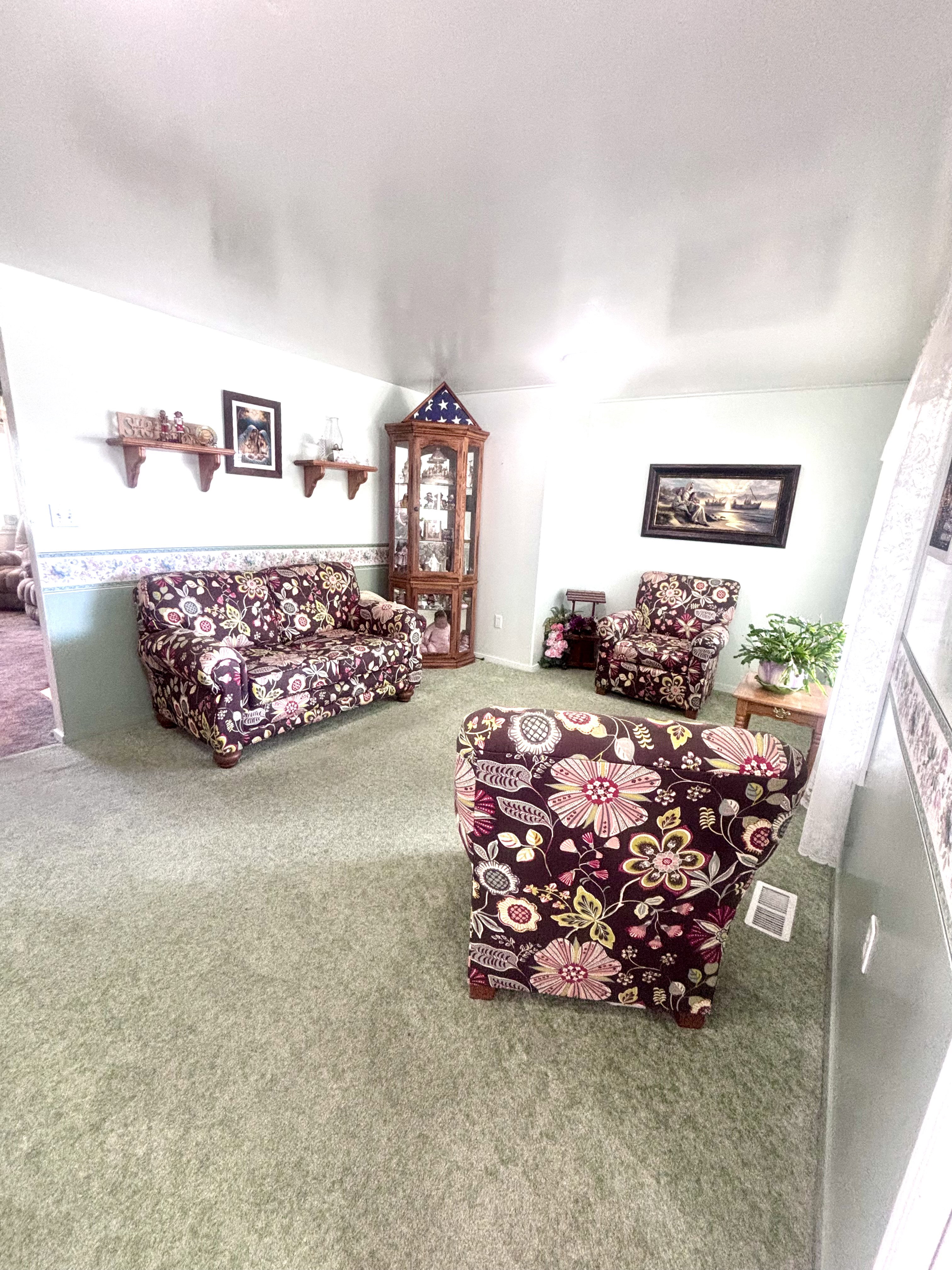 Carpeted living area featuring light green walls with a decorative border and white trim