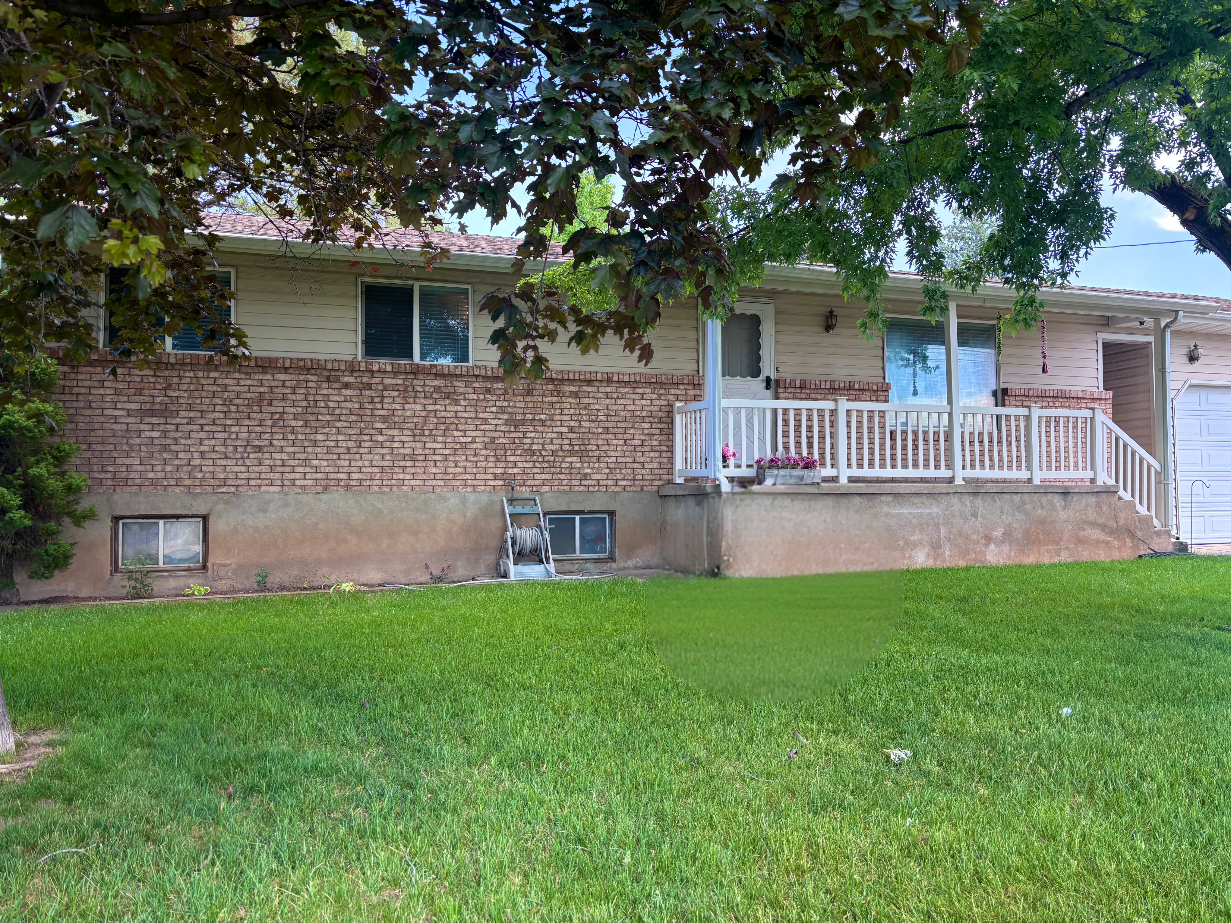 Front exterior featuring a brick facade, vinyl siding, and a covered porch with white railing
