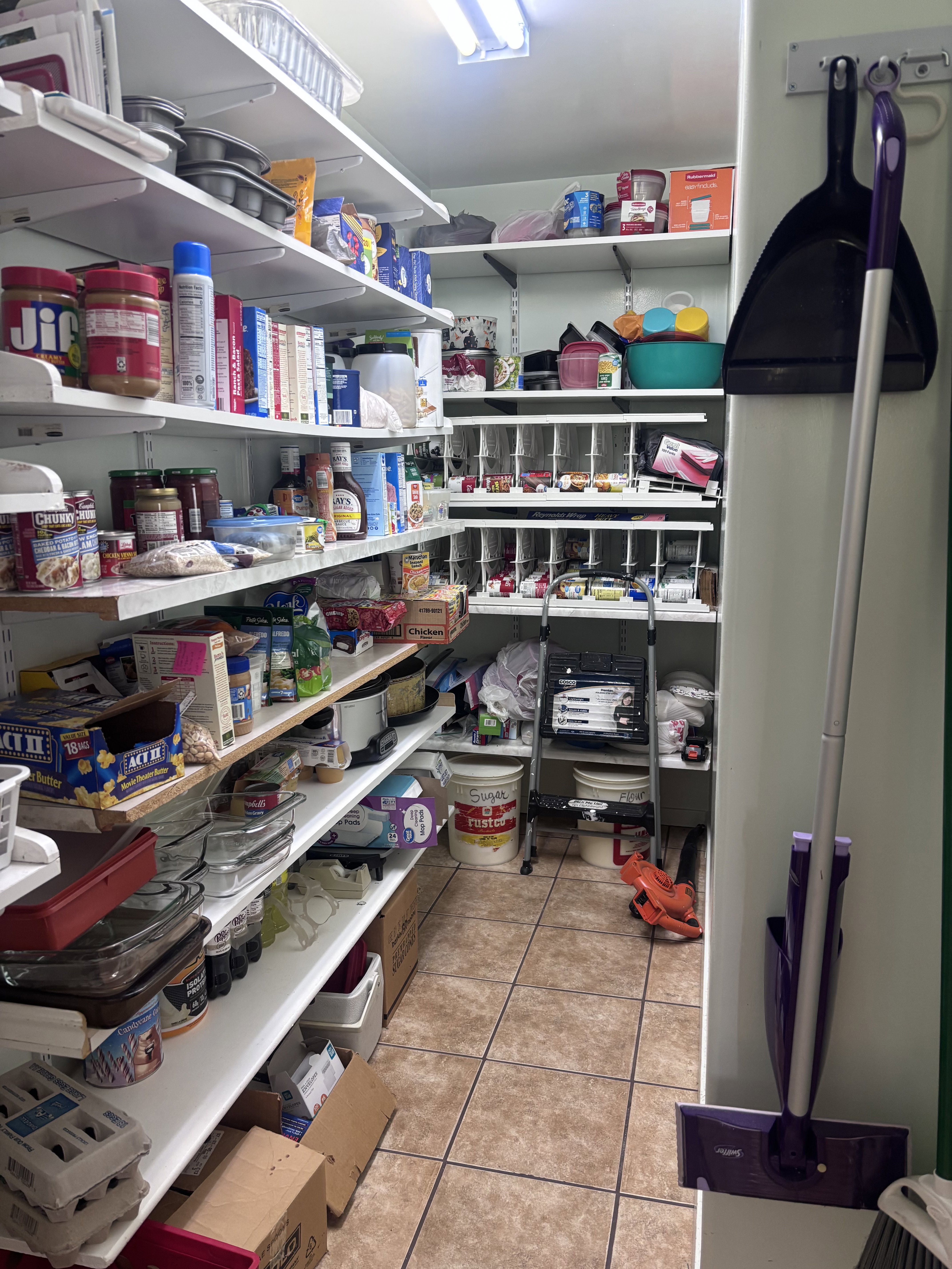 Spacious pantry featuring extensive shelving, tile flooring, and integrated lighting